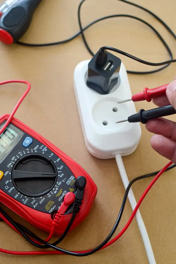 eletricista repara tomada doméstica. reparo elétrico. medição de tensão de rede